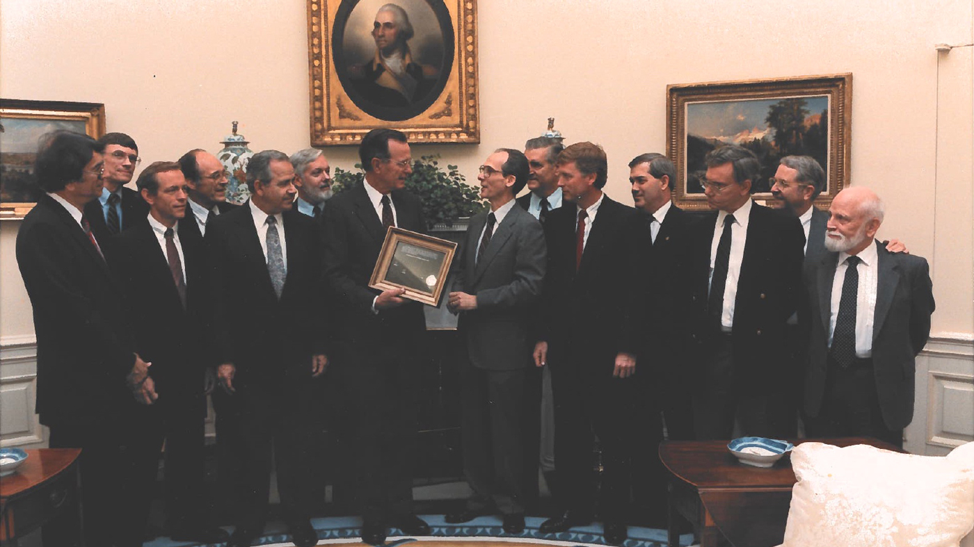 Voyager Project Scientist Ed Stone and other mission team members gave a framed copy of an iconic Voyager 1 solar system image that includes Earth as a "Pale Blue Dot" to President George H.W. Bush on June 7, 1990. The presentation was made at the White House in the Oval Office. Pictured L-R: Stamatios K. (tom) Krimgis, Barney J Conrath, Norman R. Haynes, Richard P. Laeser, George P. Textor, Lennard A. Fisk, Pres. George H.W. Bush, Edward C. Stone, Raymond L. Heacock, Earle T. Huckins, Esker K. (Ek) Davis, Adm. Richard H. Truly, Rudolf A. Hanal.